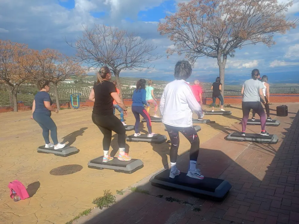 Clase de step al aire libre: alumnas sobre sus steps en una explanada, con olivos y montañas al fondo